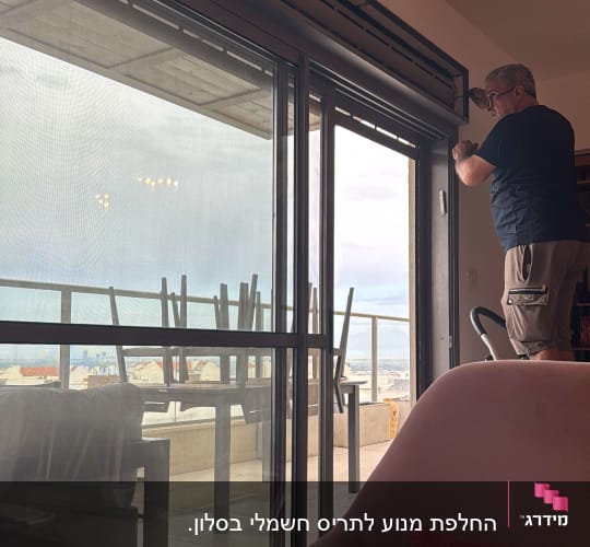 אדם מתקין תריסים על חלון זכוכית גדול